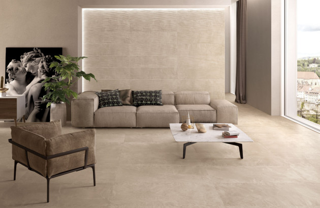 Salon élégant aux tons beiges avec canapé modulable, fauteuil assorti et carrelage effet pierre naturelle au sol.