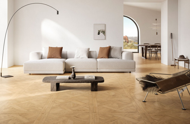 Salon lumineux au style scandinave avec canapé blanc, mobilier en bois et carrelage imitation parquet à motifs géométriques.