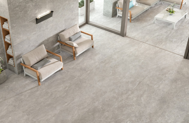 Salon moderne avec carrelage travertin gris grand format, ambiance minérale et mobilier bois pour un intérieur élégant et lumineux.