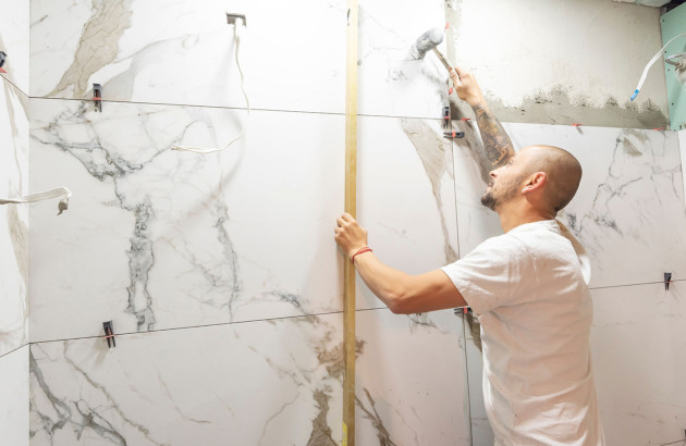 Carreleur expérimenté qui pose du carrelage en marbre sur le mur d'une salle de bains