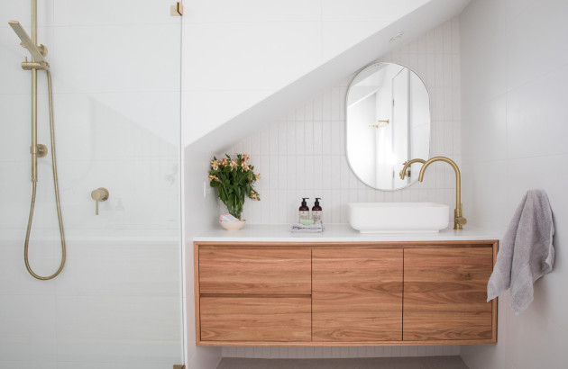 Petite salle de bains sous pente avec meuble suspendu en bois et douche à l’italienne.