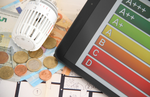 Tête thermostatique de radiateur posée sur des billets et pièces en euros à côté d’une échelle de performance énergétique.