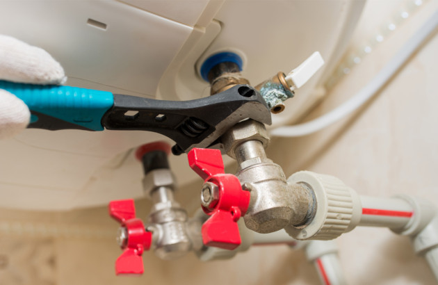 Personne qui utilise une clé à molette pour déviser un écrou de conduit.