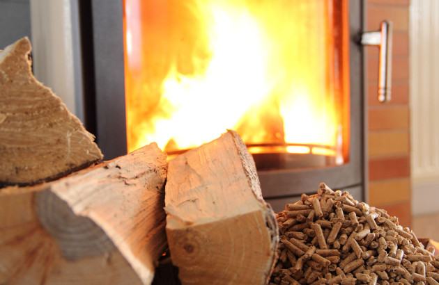 Bois de chauffage et granulés de bois devant un poêle à bois qui fonctionne
