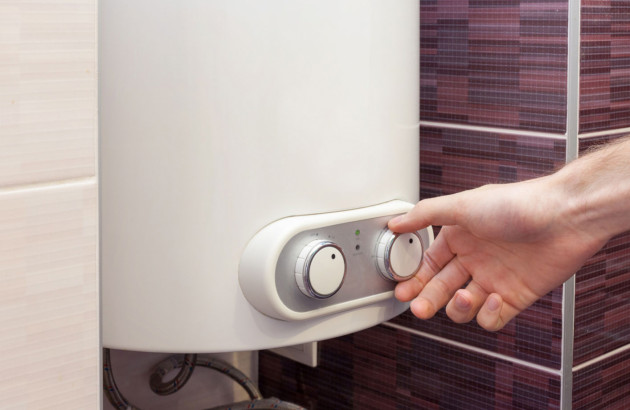 Main tournant le bouton d'un chauffe-eau