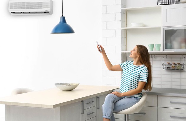 femme assise sur une chaise réglant son unité de climatisation