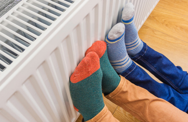 Personnes qui se réchauffent les pieds sur un radiateur avec des chausettes