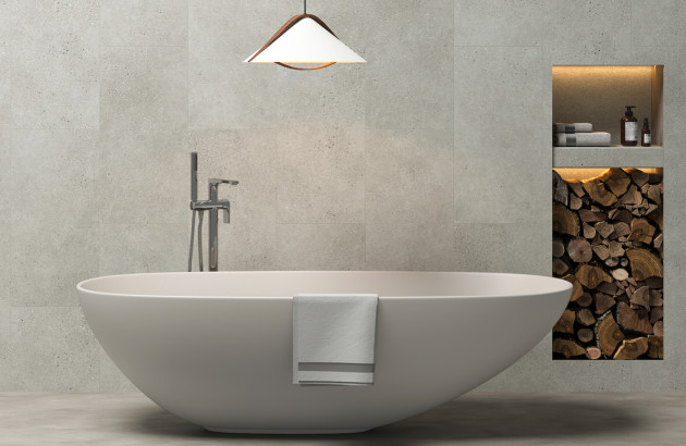 Salle de bains contemporaine avec baignoire îlot et carrelage mural texturé effet béton clair.
