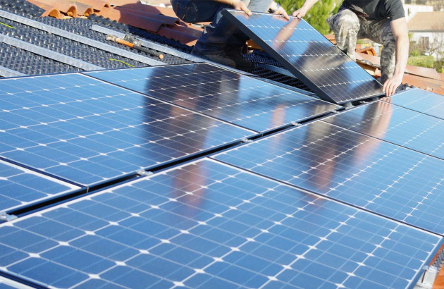 Artisans qui installent des panneaux solaires sur un toit plat