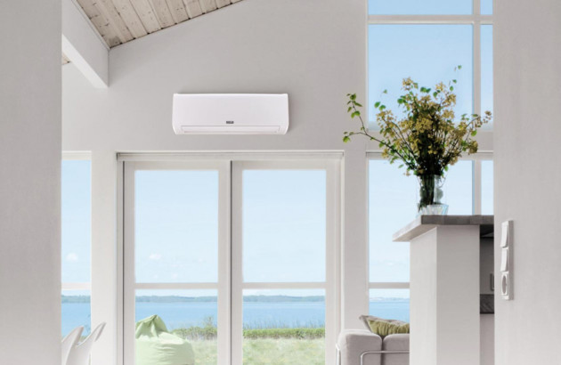 Climatisation murale réversible dans une maison lumineuse avec grande hauteur sous plafond et vue extérieure.
