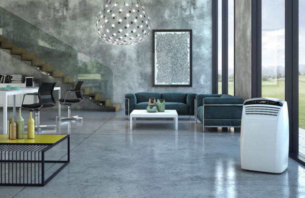 Grand séjour design avec climatiseur mobile blanc posé devant une baie vitrée dans une ambiance industrielle.