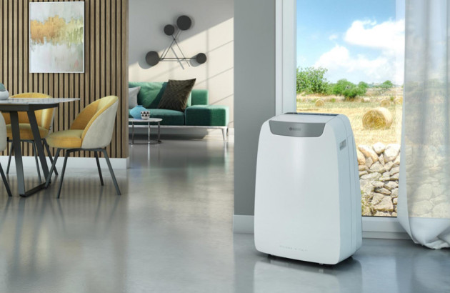 Climatiseur mobile compact dans un salon contemporain ouvert sur l’extérieur avec grande fenêtre panoramique.