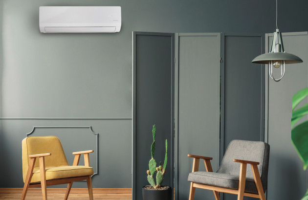 climatiseur mural blanc intégré dans un salon moderne aux murs gris anthracite avec un paravent et des fauteuils