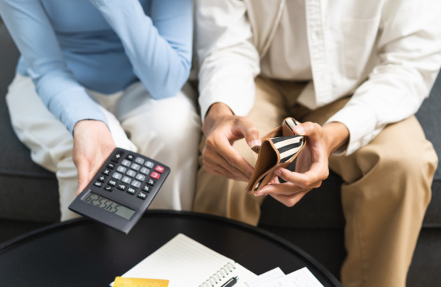 Femme et homme qui font des calculs de coût avec calculatrice et porte monnaie