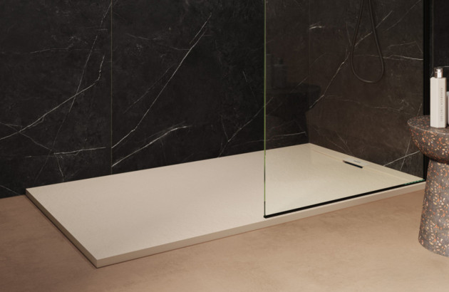 Receveur de douche blanc avec paroi vitrée et murs effet marbre noir.