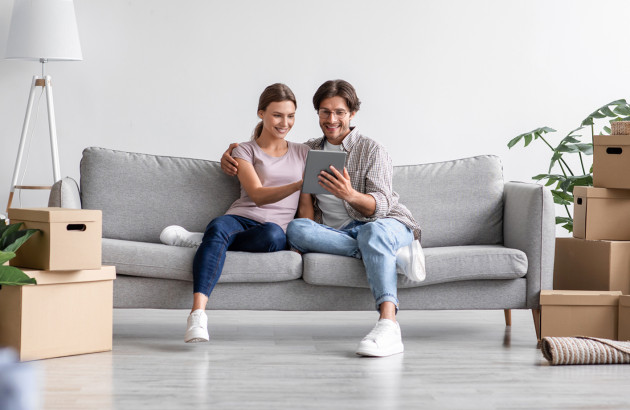 Couple utilisant une tablette dans un salon équipé d’une climatisation réversible, gestion connectée du confort