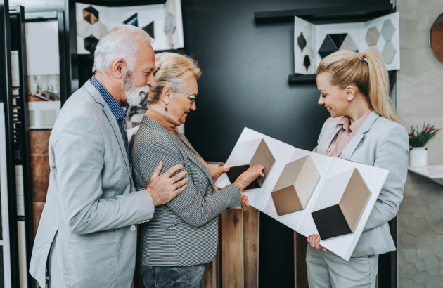 Conseillère présentant différents motifs et formats de carrelage à un couple dans un showroom.