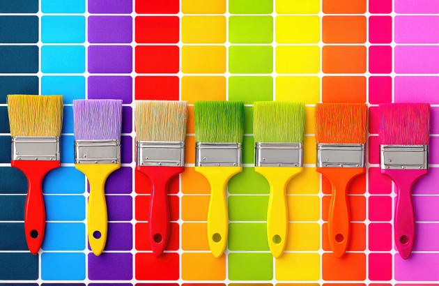 7 pinceaux de peinture posés en ligne sur des carreaux de carrelage de plusieurs couleurs