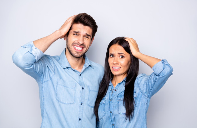 Couple qui se pose des questions, mains sur la tête, habillé en jean
