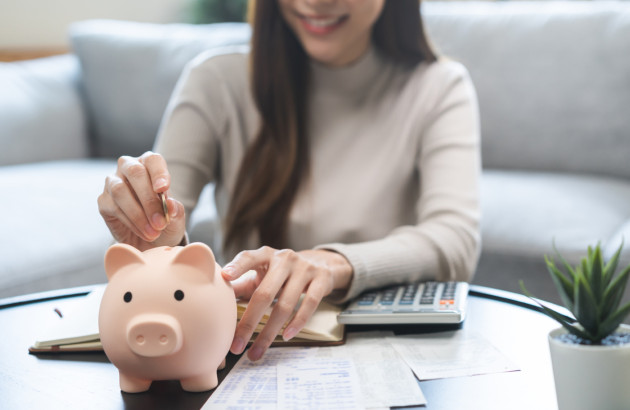 Femme mettant de l’argent dans une tirelire pour illustrer le budget d’une rénovation de salle de bains.