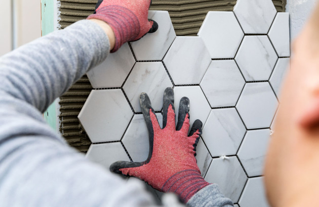Pose de carreaux hexagonaux effet marbre sur un mur.