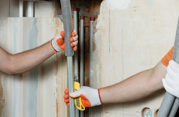 Installation d’un isolant phonique autour des tuyaux d’évacuation d’eau encastrés dans une cloison.