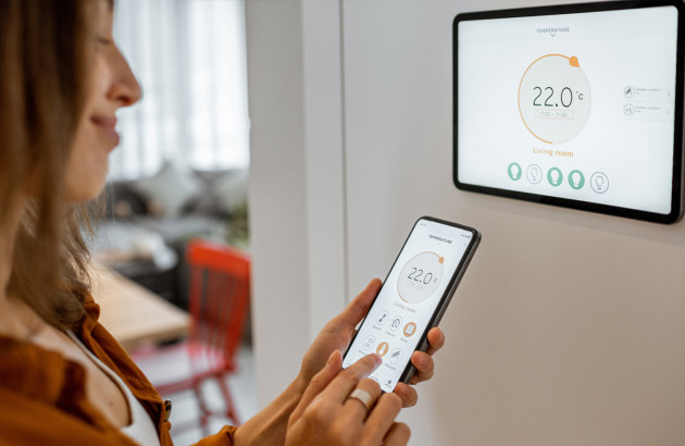 Femme qui contrôle son thermostat d'ambiance programmable avec son téléphone
