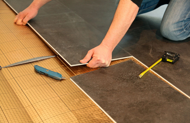 Homme posant du carrelage gris anthracite sur un film isolant