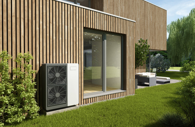 Unité extérieure de pompe à chaleur devant maison en bois