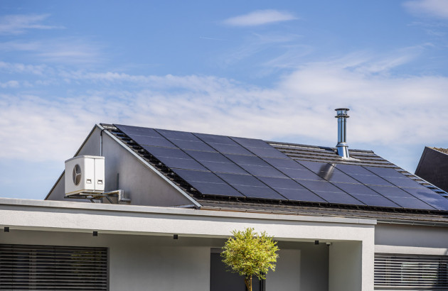 Toiture résidentielle avec panneaux solaires et climatisation extérieure