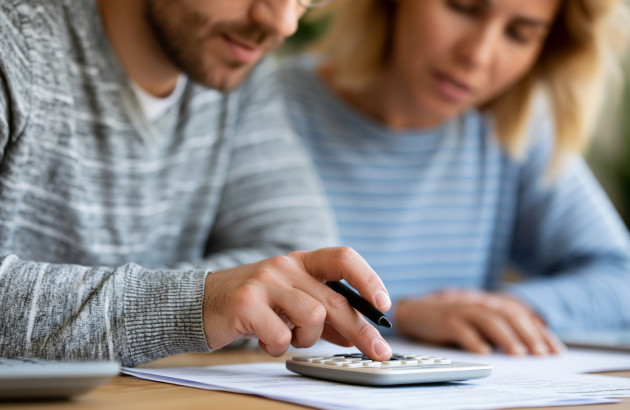 Couple utilisant une calculatrice pour estimer le budget et la rentabilité d'une installation de panneaux solaires.