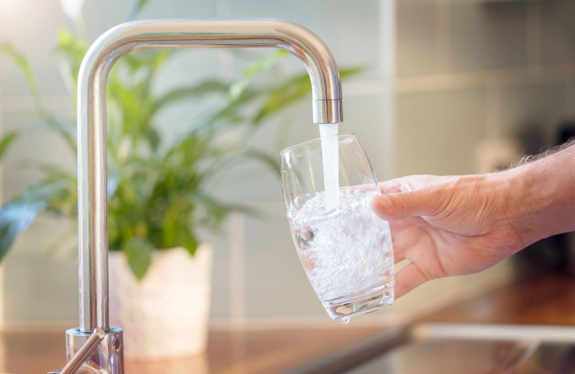 Personne remplissant un verre d'eau du robinet