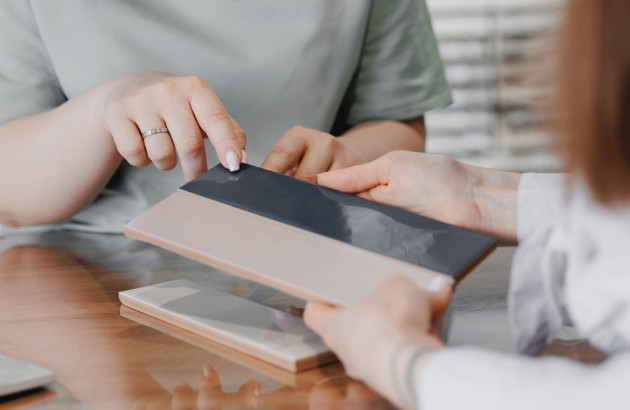 Comparaison d’échantillons de carrelage sur table, choix des couleurs et finitions avec un conseiller