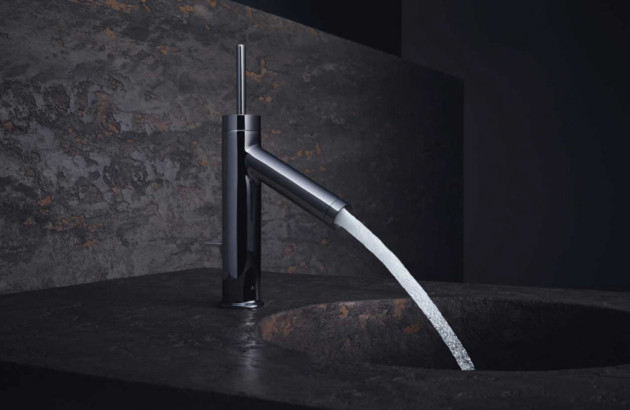 Mitigeur de salle de bains contemporain à effet cascade installé sur un plan vasque sombre au style minéral.