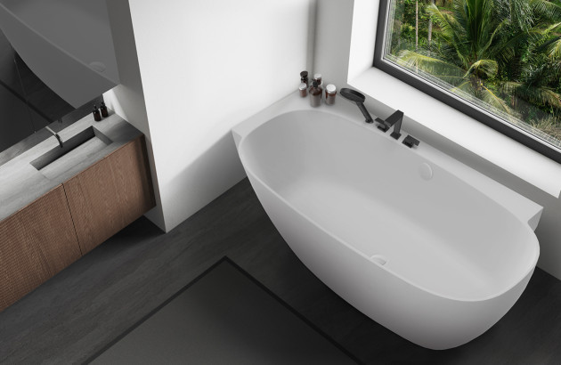 Baignoire îlot blanche installée près d’une grande fenêtre dans une salle de bains moderne aux tons sombres.
