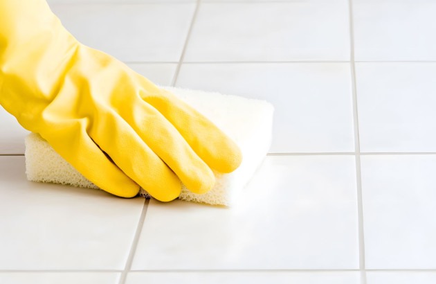 Personne qui passe l'éponge sur du carrelage blanc
