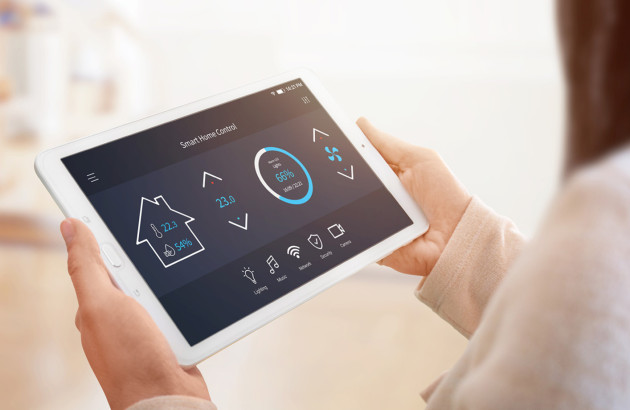 Femme qui contrôle son thermostat d'ambiance programmable avec une tablette