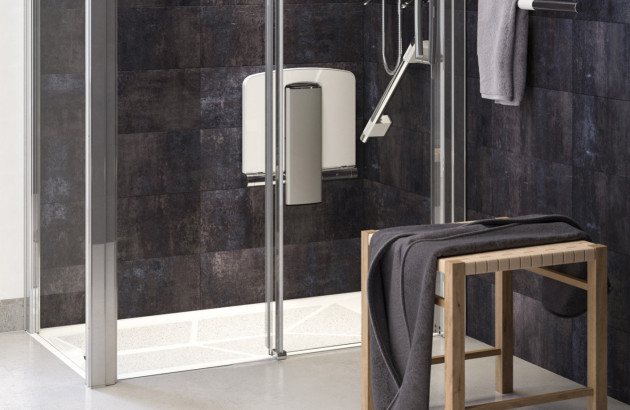 Tabouret de douche PMR rabattable installé dans une douche moderne avec parois vitrées.