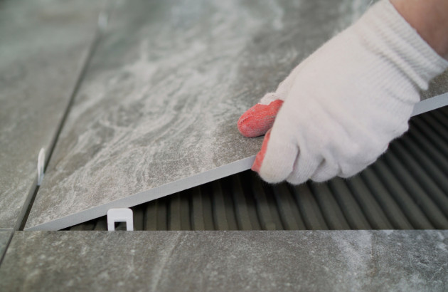 Pose de carrelage travertin gris avec système de nivellement pour un rendu uniforme et professionnel.