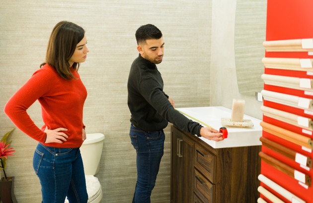 Femme qui regarde un homme mesurer la longueur d'un meuble vasque de salle de bains