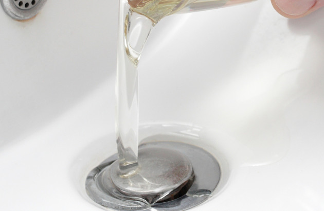 Personne qui verse un verre d'eau dans un lavabo