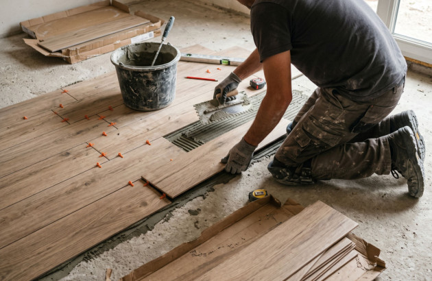 Carreleur qui pose du carrelage imitation parquet