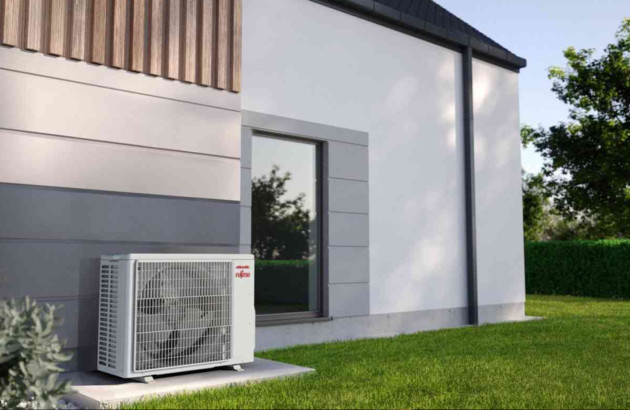 Unité extérieure de climatisation installée sur terrasse moderne, système split relié à une maison contemporaine