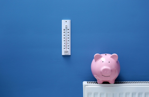 Cochon tirelire sur un radiateur et thermomètre accroché sur un mur bleu
