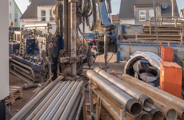 Chantier de forage géothermique résidentiel avec machine de forage et tubes de captage au sol.
