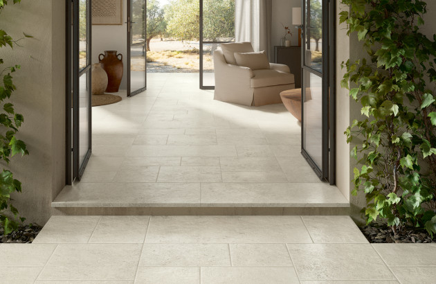 Sol extérieur en carrelage clair reliant harmonieusement la terrasse et l’intérieur de la maison.