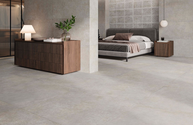 Chambre contemporaine avec carrelage effet béton ciré, lit design, mobilier en bois et ambiance épurée.