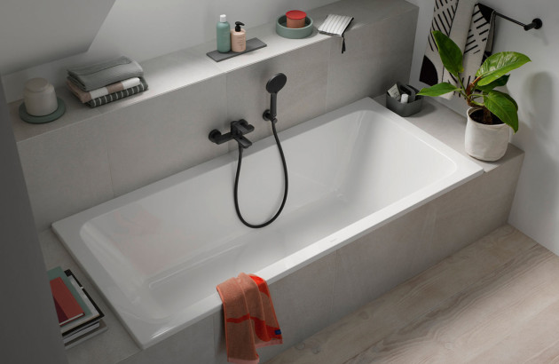 Baignoire encastrée sous pente avec robinetterie noire mate dans une salle de bains optimisée pour les petits espaces.