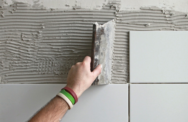 fixation des carreaux blancs au sol à l'aide d'un mortier-colle