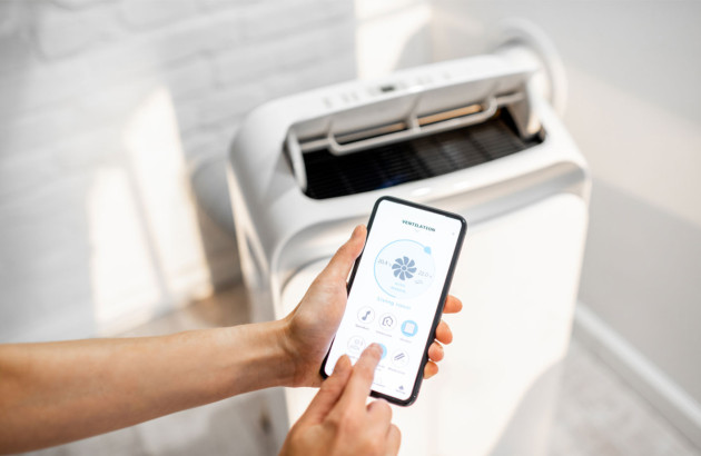 personne qui règle sur son smartphone la climatisation mobile